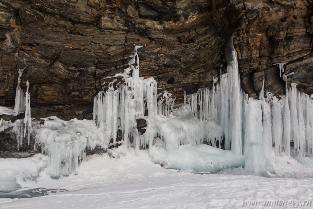 D04B8330.JPG - The rock on the frozen lake Baikal is covered with a thick layer of blue ice: many icicles and splashes
