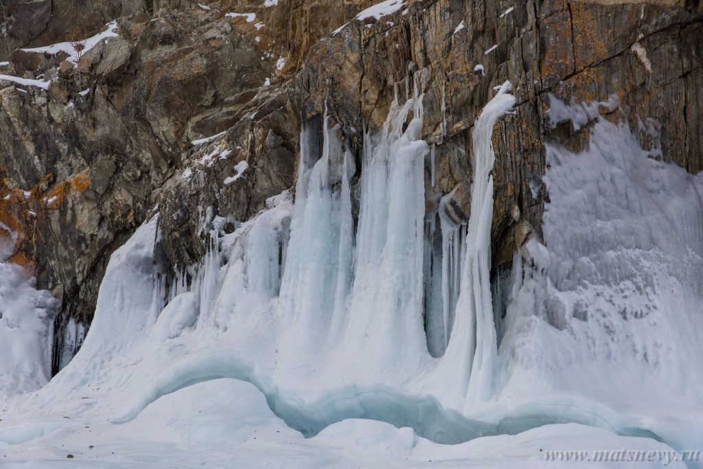 D04B8802.JPG - The rock on the frozen lake Baikal is covered with a thick layer of blue ice: many icicles and splashes