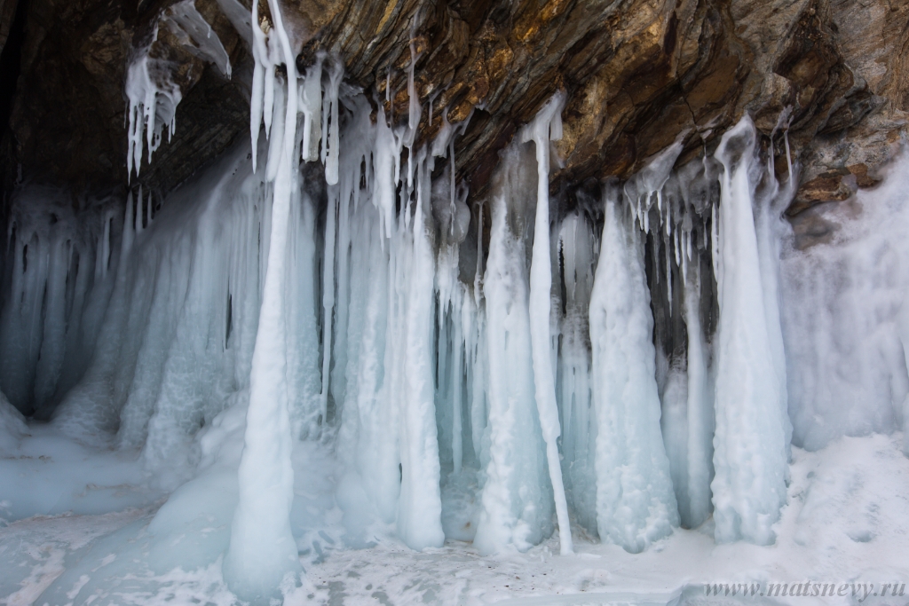 D04B8824.JPG - The rock on the frozen lake Baikal is covered with a thick layer of blue ice: many icicles and splashes