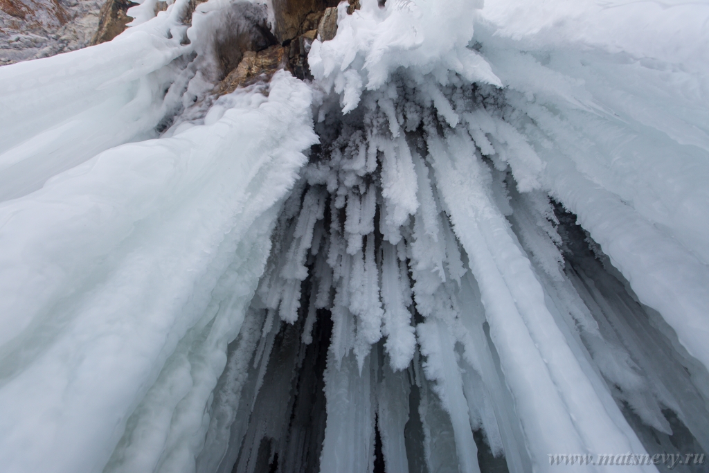 D04B8828.JPG - The rock on the frozen lake Baikal is covered with a thick layer of blue ice: many icicles and splashes