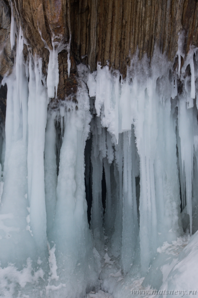 D04B8834.JPG - The rock on the frozen lake Baikal is covered with a thick layer of blue ice: many icicles and splashes